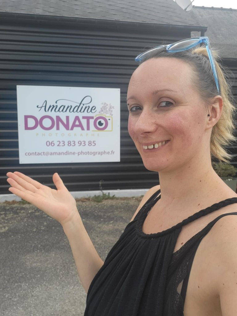 Amandine Donato, photographe professionnelle à Josselin dans le Morbihan, pose devant son enseigne pour présenter son activité sur son blog.