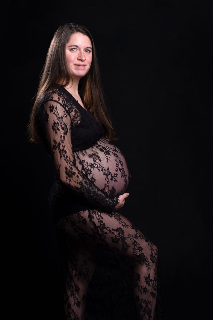 Portrait d’une femme enceinte en robe noire en dentelle lors d’une séance photo grossesse en studio à Josselin, par Amandine Donato, photographe professionnelle.